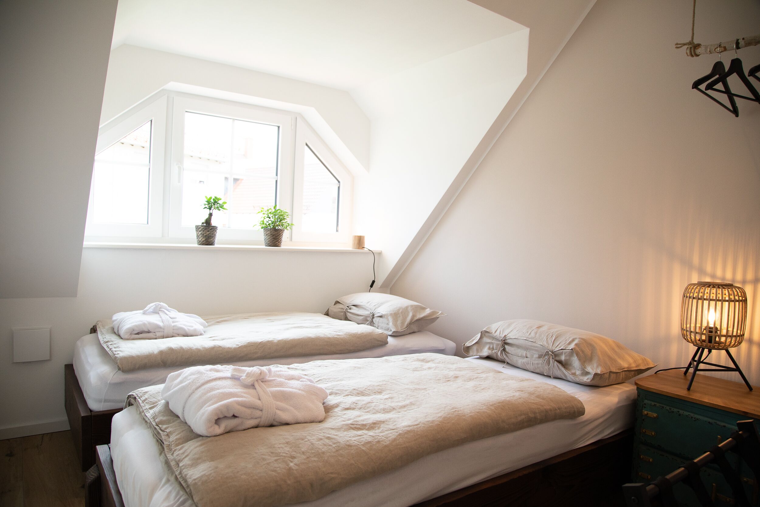 Un dormitorio con dos camas, una ventana y una lámpara de noche.