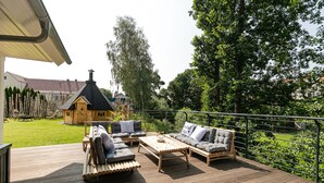 A wooden deck with outdoor furniture, including sofas and a coffee table. - Vacation home Heuliebe, barbecue hut, whirlpool, outdoor sauna (Herbstein)