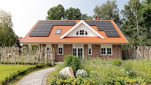 A house with a red-tiled roof, solar panels, and a brick exterior. - Vacation home Heuliebe, barbecue hut, whirlpool, outdoor sauna (Herbstein)
