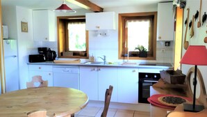 Una cucina con mobili bianchi, un tavolo di legno e una lampada rossa.