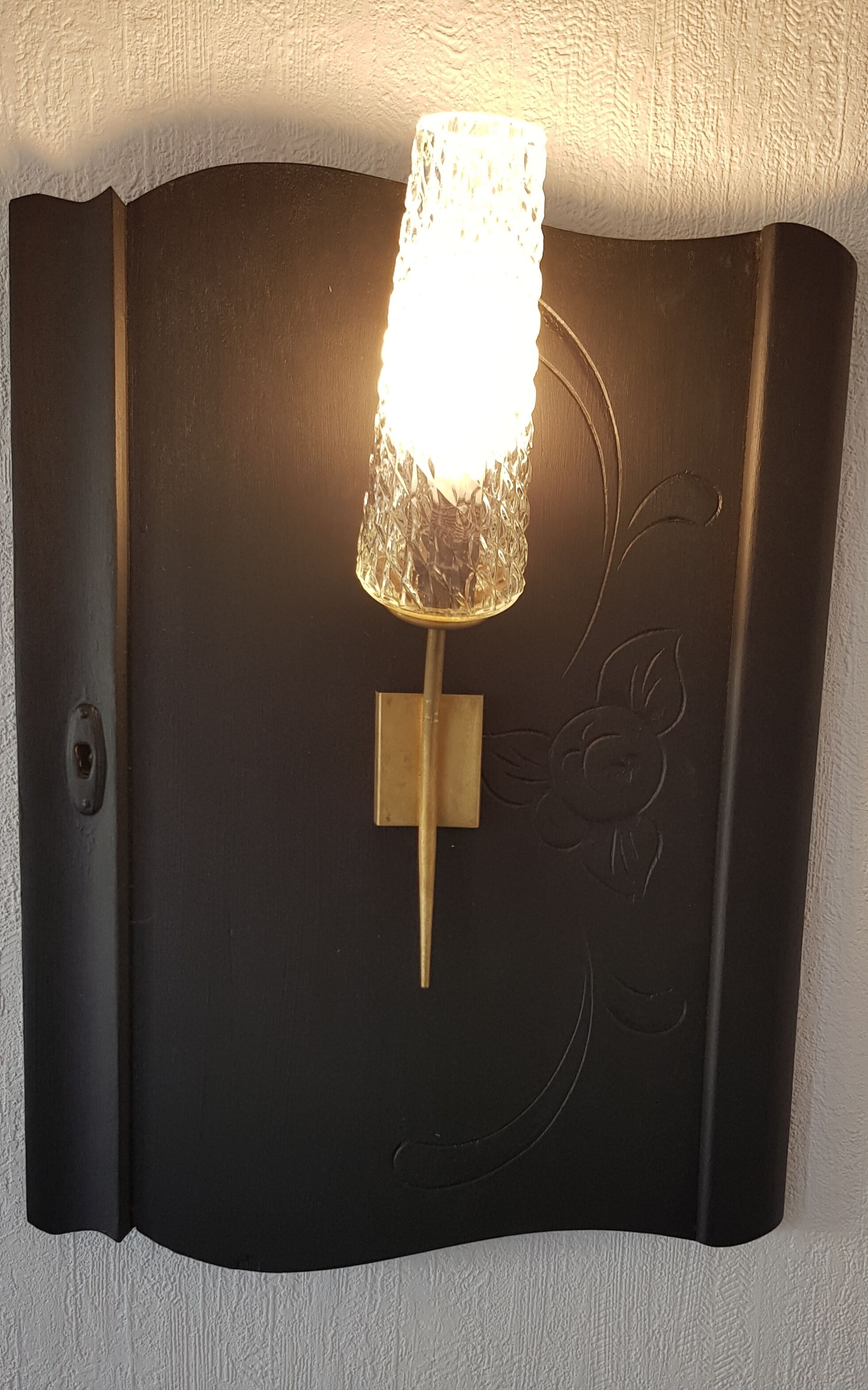 Un luminaire mural avec un abat-jour en verre texturé et un socle de couleur dorée.