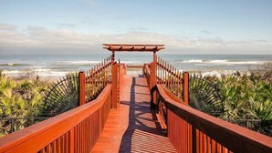 A wooden boardwalk leading to a beach with a view of the ocean. - New Furnishings, Direct Oceanfront Corner Unit 721! (Palm Coast)
