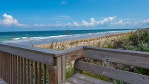 A wooden deck overlooking a beach with waves, sand, and sparse vegetation. - New Furnishings, Direct Oceanfront Corner Unit 721! (Palm Coast)