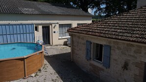 Et lille hus med swimmingpool, stenvæg og tagdækning af fliser.