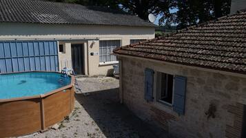 Una piccola casa con piscina, un muro in pietra e un tetto in tegole.