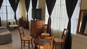 En stue med sofa, stole, fjernsyn og skab.