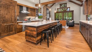 A spacious kitchen with a large island, wooden cabinets, and a stone backsplash.