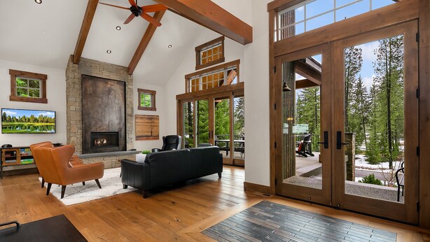A spacious living room with a fireplace, leather sofas, and a large sliding glass door leading to a deck.