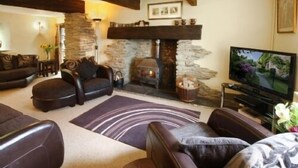A cozy living room with a stone fireplace, leather sofas, and a flat-screen TV. - The Farmhouse - perfect for families to share, private hot-tub and fabulous shared leisure facilitie (Boncath,)