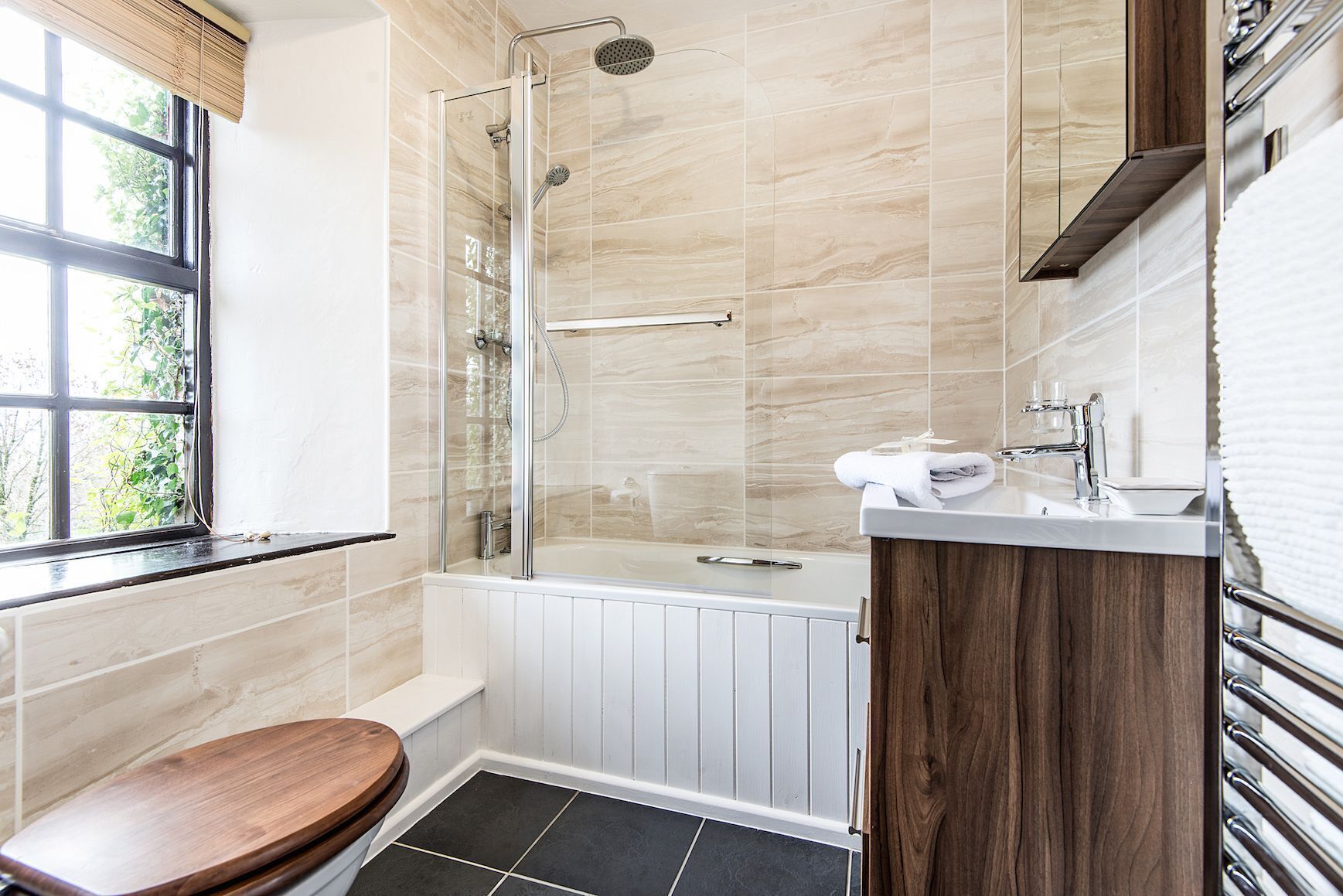 A modern bathroom with a glass-enclosed shower, a bathtub, and a toilet.
