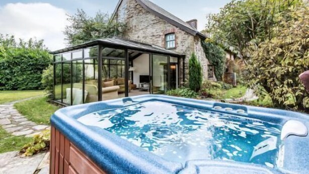 A stone house with a glass conservatory and a hot tub in the foreground. - The Farmhouse - perfect for families to share, private hot-tub and fabulous shared leisure facilitie (Boncath,)