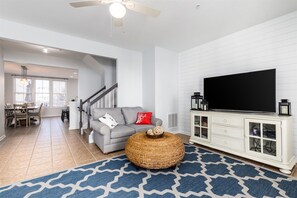 A living room with a television, a sofa, a coffee table, and a staircase leading to another room. - Sunset Island 20 Beach Side Drive (Ocean City)