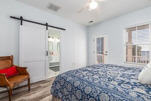 A bedroom with a bed, a chair, a sliding door, and a window with blinds. - Sunset Island 20 Beach Side Drive (Ocean City)