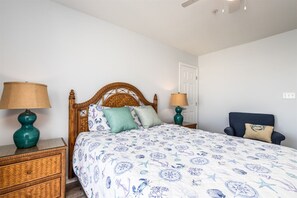 A bedroom with a bed, two nightstands, a chair, and a door. - Sunset Island 20 Beach Side Drive (Ocean City)