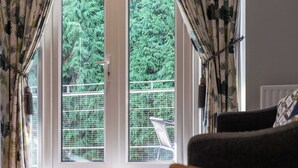 Una habitación con un ventanal grande, cortinas y una silla.