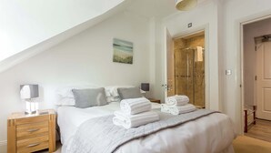 Un dormitorio con cama, mesita de noche, un cuadro y zona de ducha.