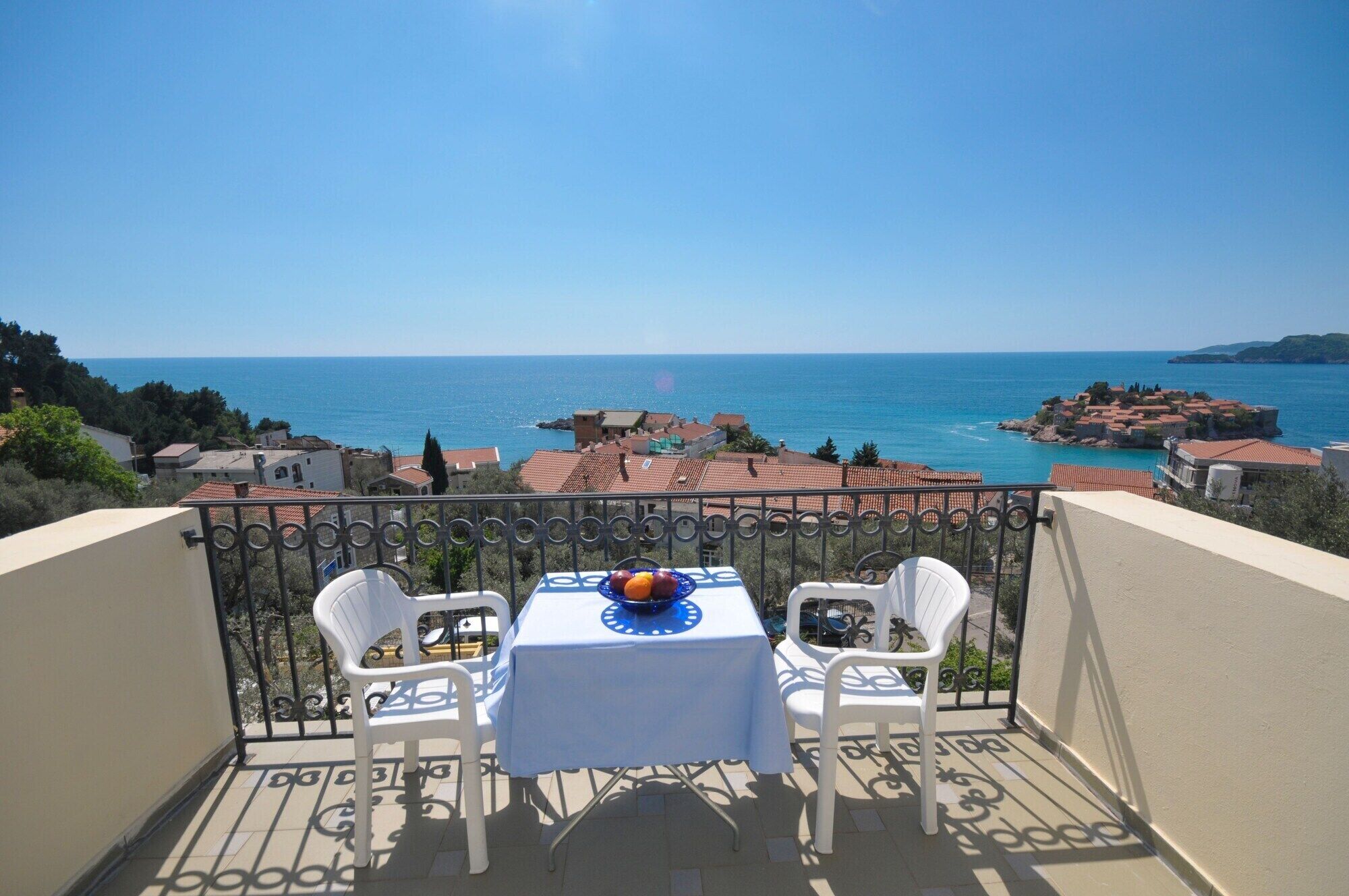 A balcony with a table and chairs overlooking a coastal view.
