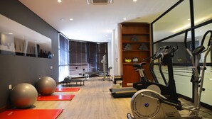 Ein Fitnessraum mit Trainingsgeräten, roten Matten und Holzboden.