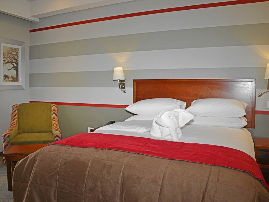 A hotel room with a bed, a chair, and a nightstand.