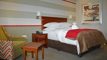 Quarto de hotel com uma cama, uma cadeira, uma mesa e um quadro na parede.