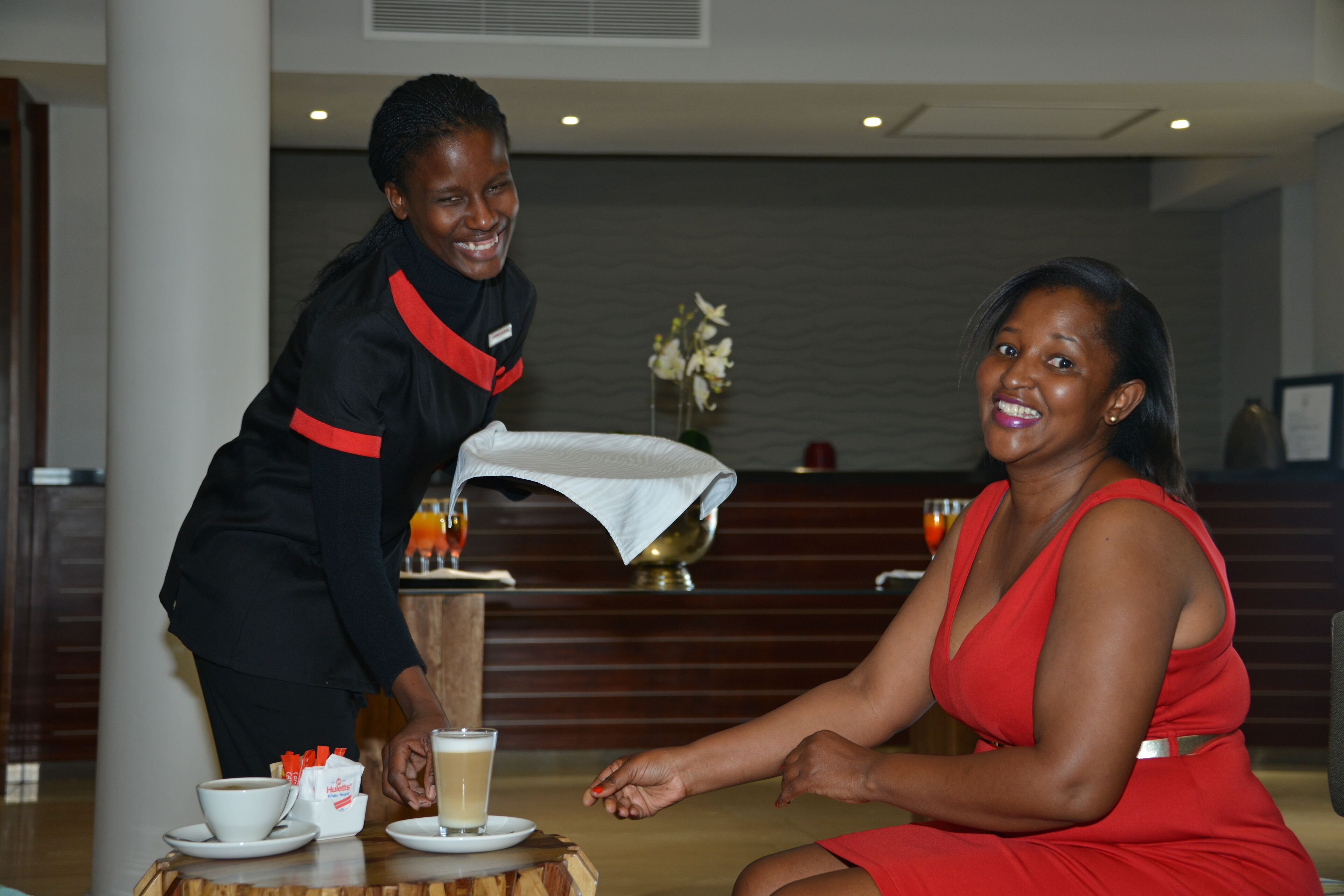 Un hall de hotel con mostrador de recepción, estación de café y zona de estar.