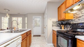 Une cuisine moderne avec des meubles en bois, un évier en acier inoxydable et une cuisinière noire.