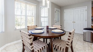 Un coin repas avec une table ronde, six chaises et un lustre.