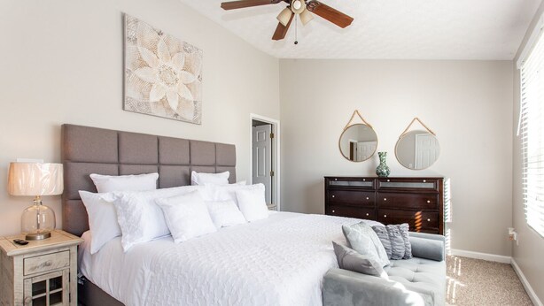 Une chambre à coucher comprenant un lit, une table de chevet, une commode et deux miroirs ronds.