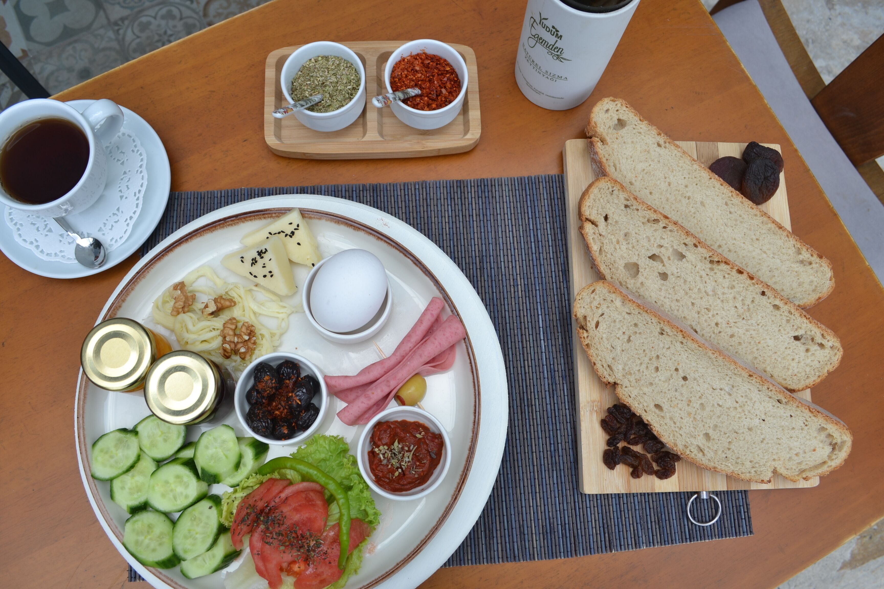 Een ontbijtplateau met brood, eieren, kaas en verschillende soorten beleg op een houten tafel.