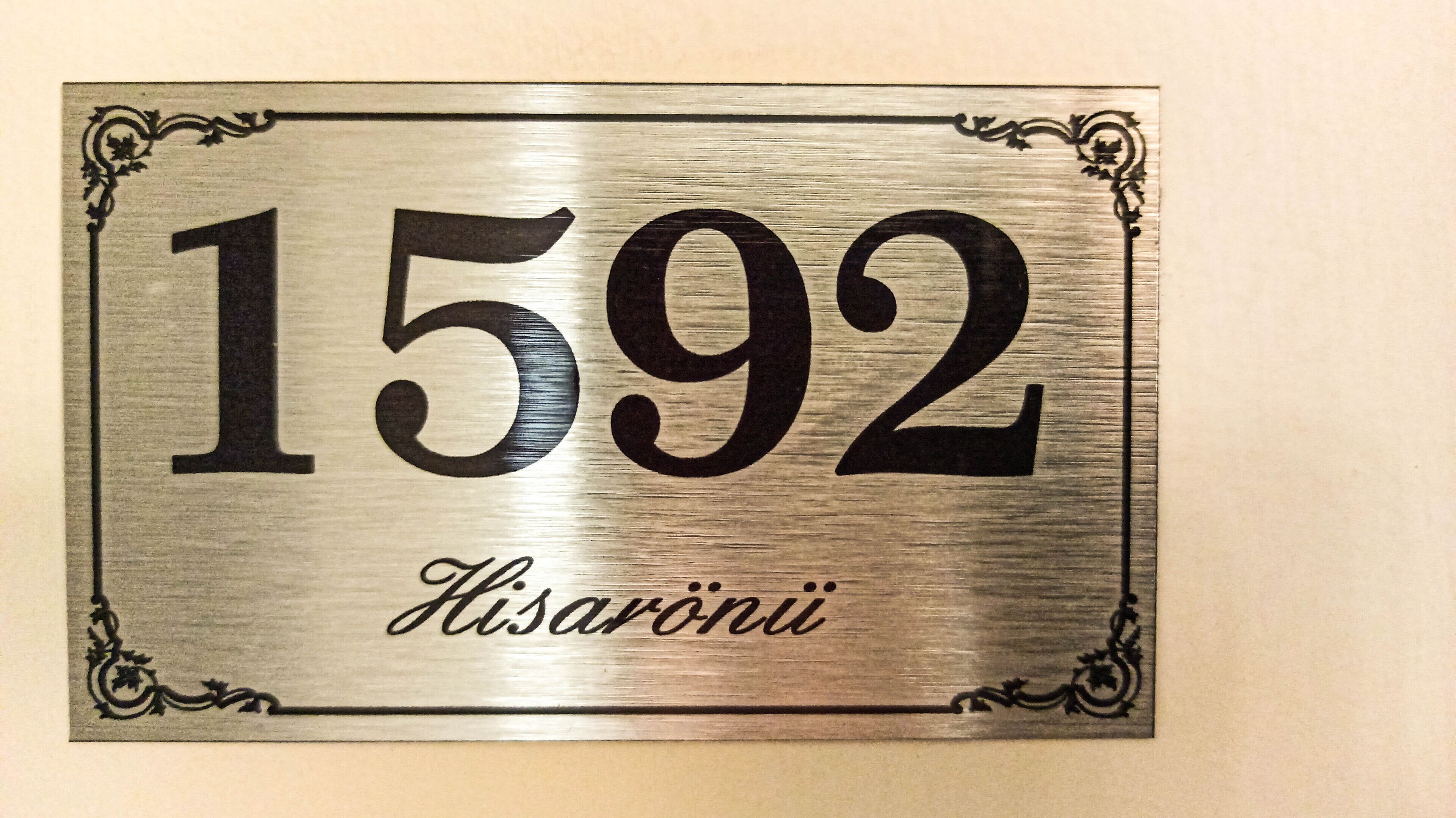 A metal plaque with the number 1592 and the word 'Hisaroni' engraved on it.