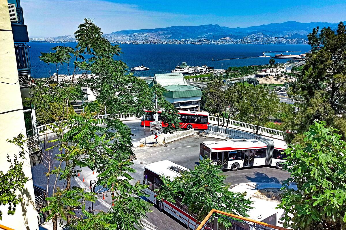Un paisaje urbano costero con vista al mar, una estación de autobuses y edificios circundantes.