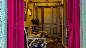 A hallway with a chandelier, two chairs with floral upholstery, and a door with a decorative handle. - Variante Hotel (Izmir)