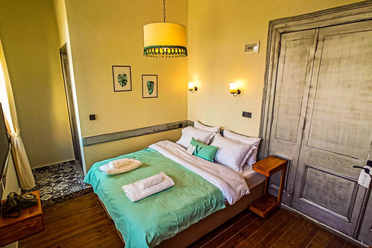 Un dormitorio ordenado con cama, mesitas de noche, una lámpara y una puerta.