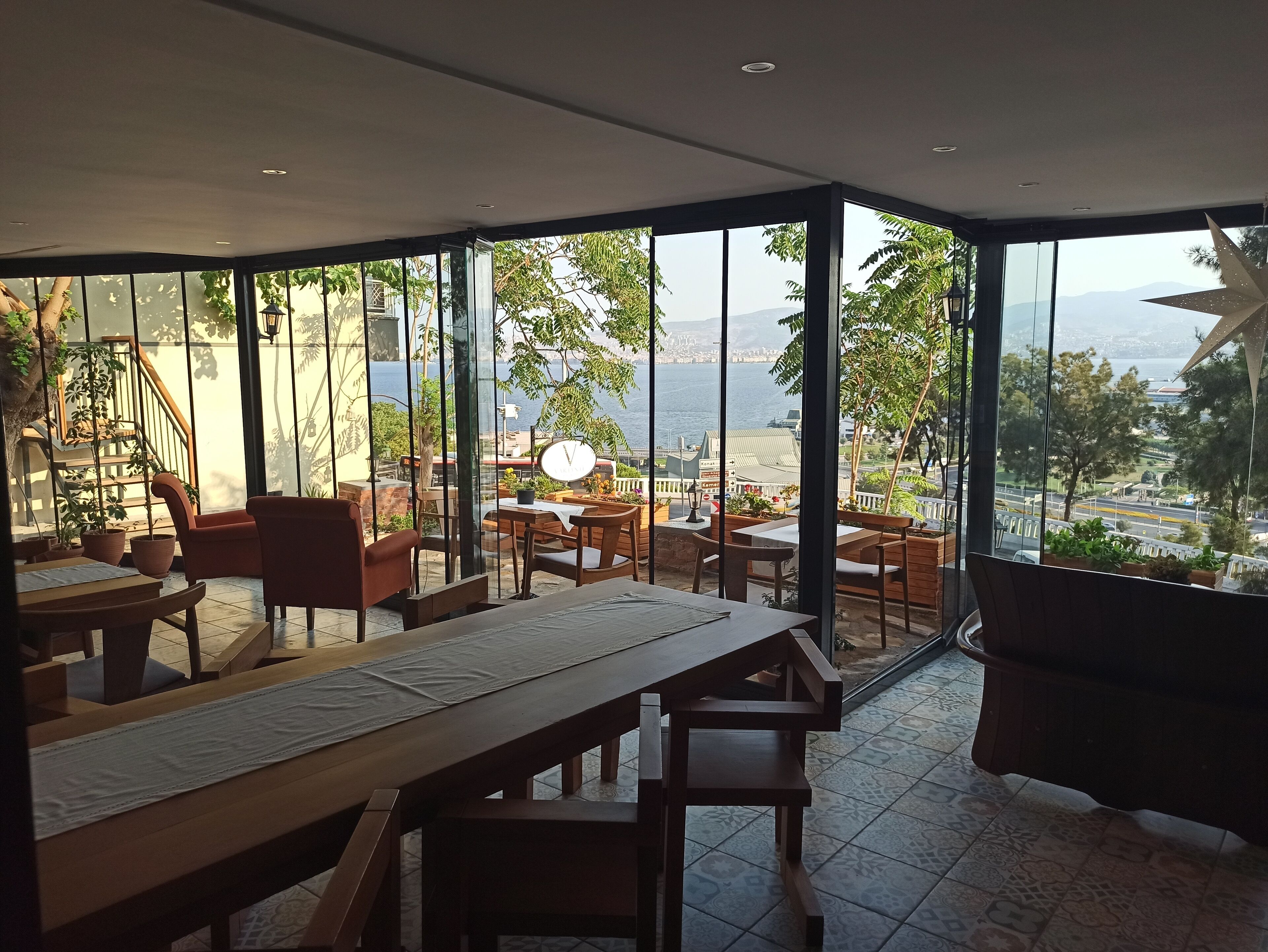 A restaurant with a terrace overlooking a scenic view of the sea and cityscape.