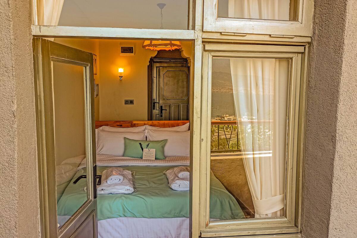 Una habitación con una cama, un espejo y vistas al exterior.