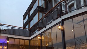 A building with a glass facade, outdoor seating area, and a stone wall. - Variante Hotel (Izmir)