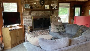 Un salon chaleureux avec une cheminée, un téléviseur et un canapé confortable.