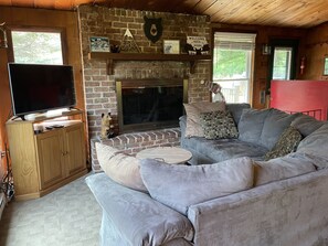 Uma sala de estar acolhedora com lareira, televisão e um sofá confortável.
