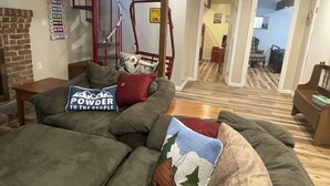 Un salon chaleureux avec un canapé, une table basse et un escalier menant à une autre pièce.