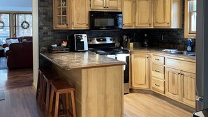 A modern kitchen with wooden cabinets, a central island, and a built-in stove. - Premier Cottage Getaway-Acorn Grove, Pentwater, MI (Pentwater)