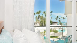 Habitació d'hotel amb balcó i vista a una piscina i palmeres.