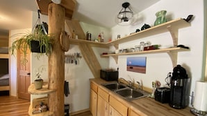 Una cocina con armarios de madera, un lavamanos, una cafetera y una planta colgante.