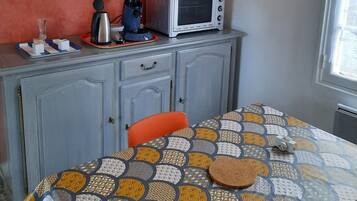 A small kitchen with a microwave, a kettle, and a clock on the wall.