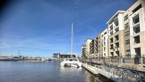 Een jachthaven met een witte boot in de haven, gebouwen met balkons, en een heldere lucht.
