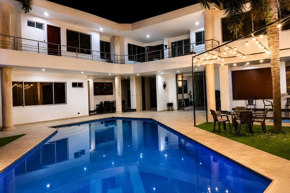 A multi-level residential building with a swimming pool, outdoor seating, and a balcony.