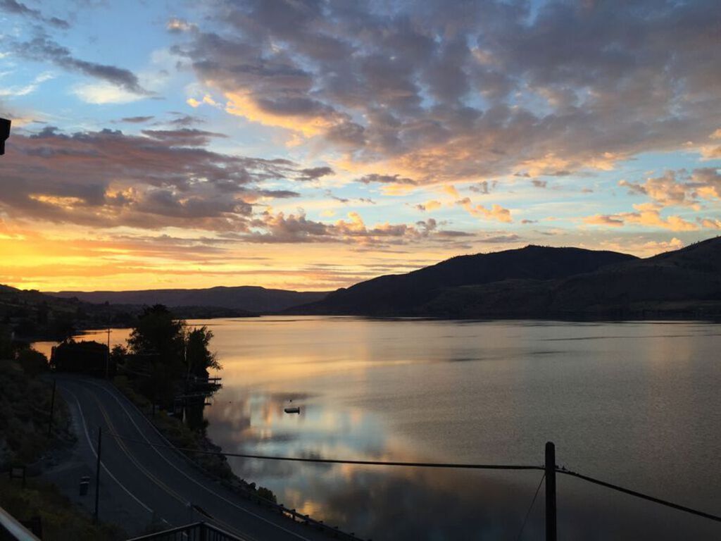 A calm lake at sunset with a road curving along the shore.