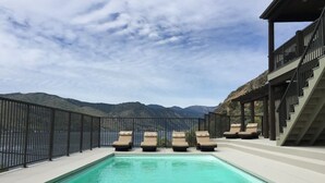 A swimming pool with lounge chairs, a fenced area, and a view of mountains. - WATER FRONT - PRIVATE POOL AND DOCK W/BUOY (Manson)