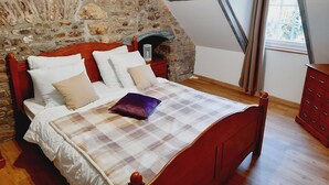 Un dormitorio con pared de piedra, cama de madera y ventana.