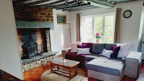 Una sala de estar acogedora con chimenea, un sofá, una mesita de centro y una ventana con cortinas.