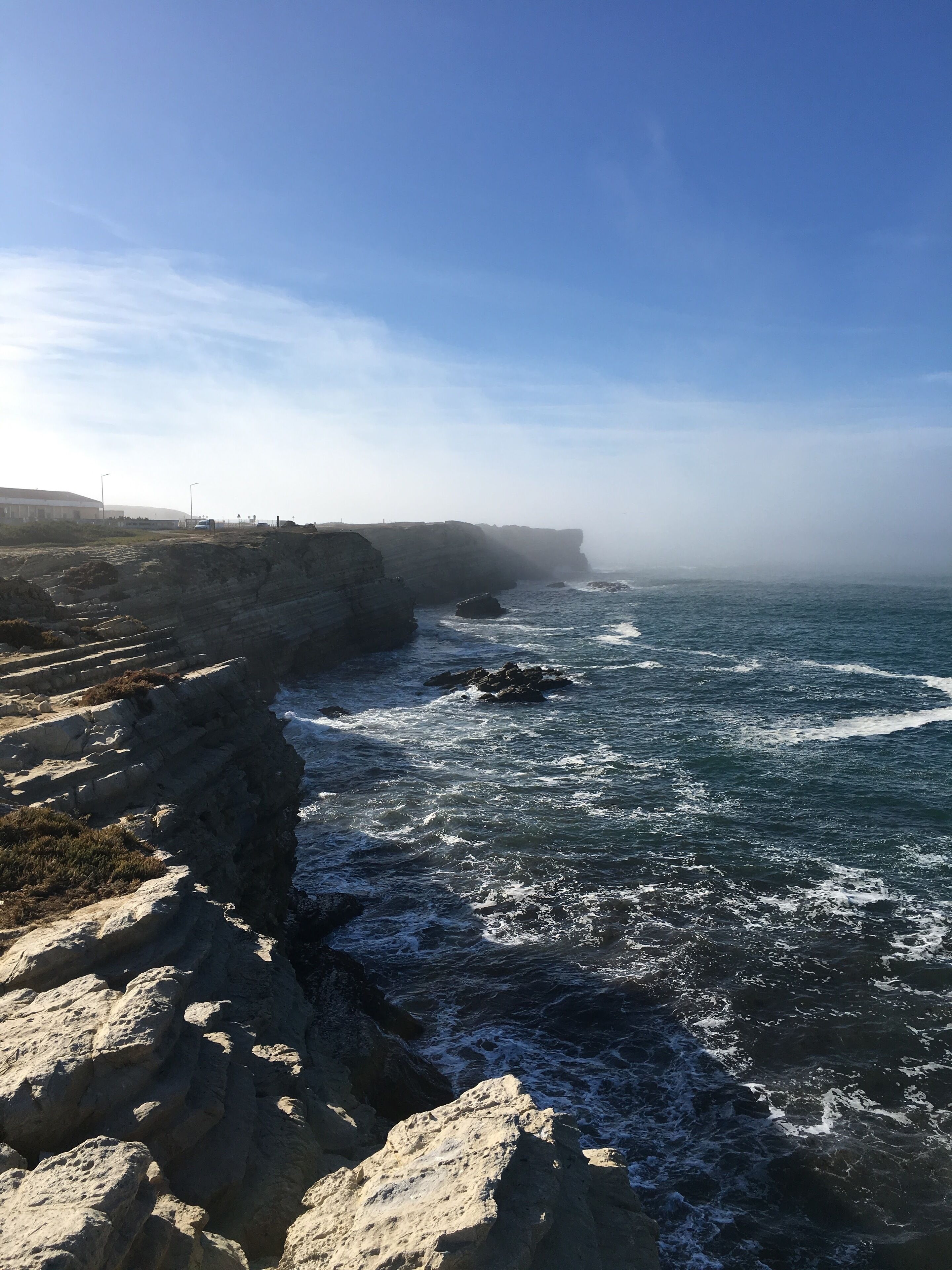 Un paisaje costero con acantilados rocosos y olas rompiendo en la orilla.